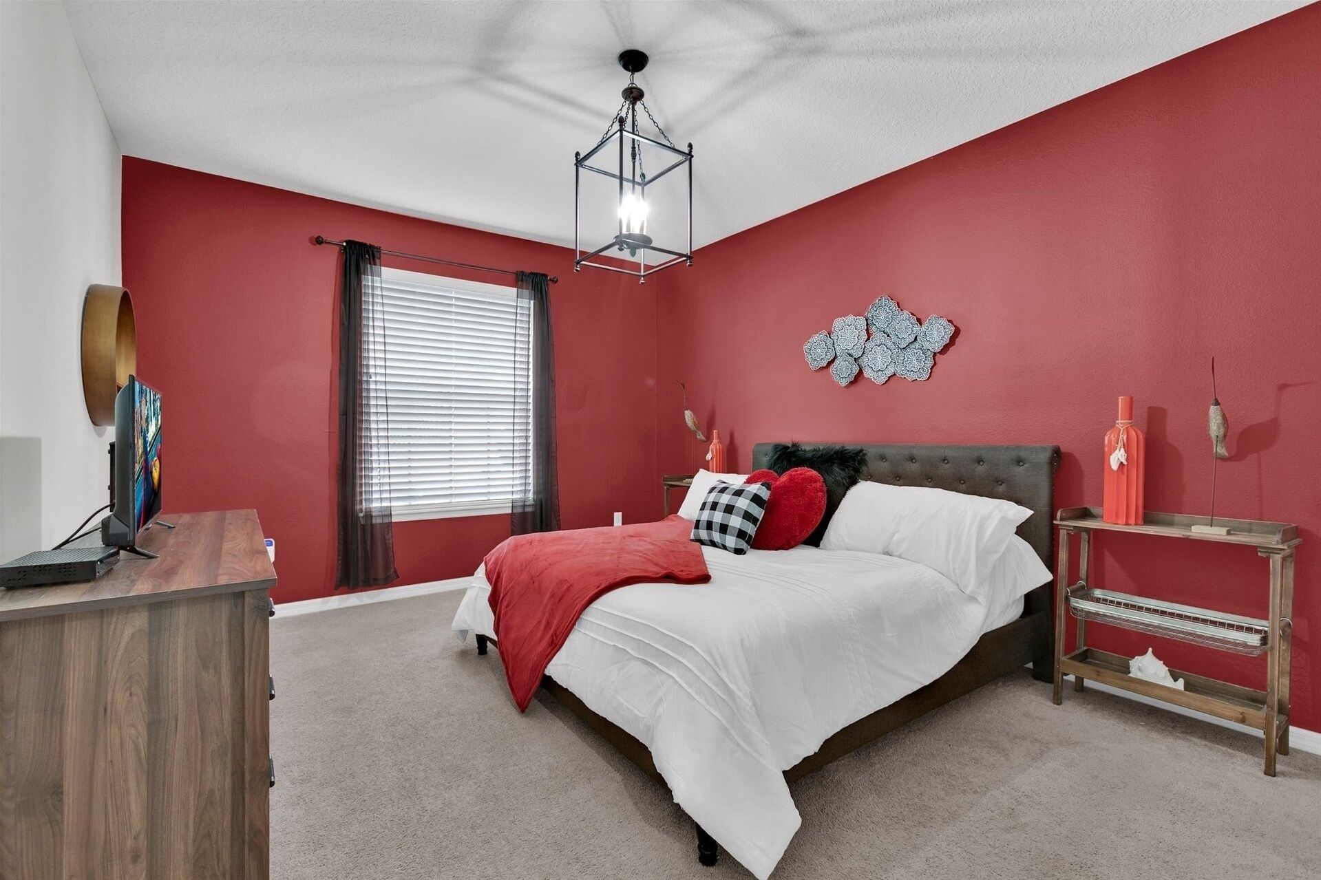 A bedroom with a bed, a desk, a chair, a lamp, and a window with blinds.