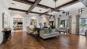 A spacious living room with hardwood flooring, a sofa set, a dining area with a bar, and a large window with curtains. - Solara Resort 9 Bedroom Private Pool Home 9 Home (Kissimmee)
