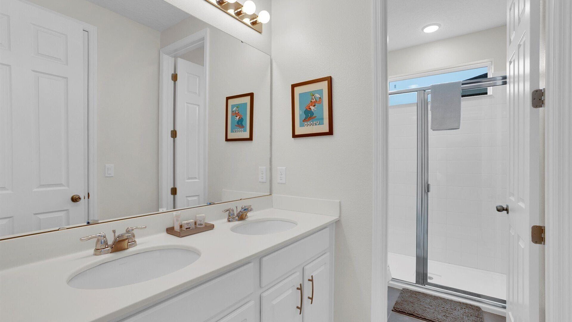 Une salle de bain avec deux lavabos, un grand miroir et un espace douche.