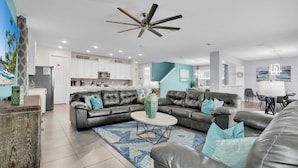 A modern living room with a leather sofa, a coffee table, and a dining area with a table and chairs. - Solara Resort 9 Bedroom Private Pool Home 9 Home (Kissimmee)