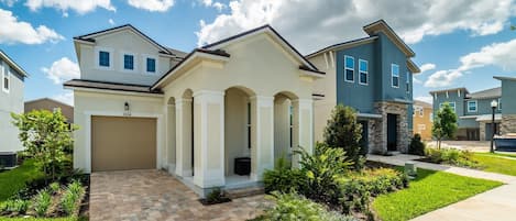 Una casa moderna de dos pisos con garaje, un porche cubierto y un jardín delantero ajardinado.