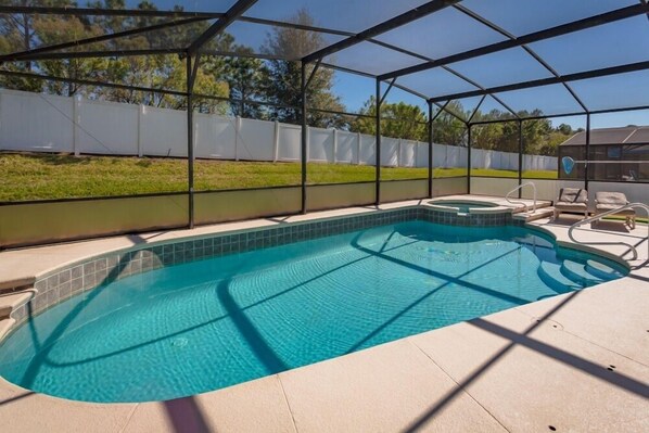 Une piscine couverte avec un jacuzzi et des chaises longues.