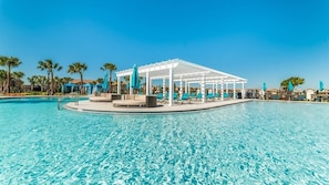 Une piscine agrémentée d’une pergola blanche et de chaises longues, le tout entouré de palmiers.