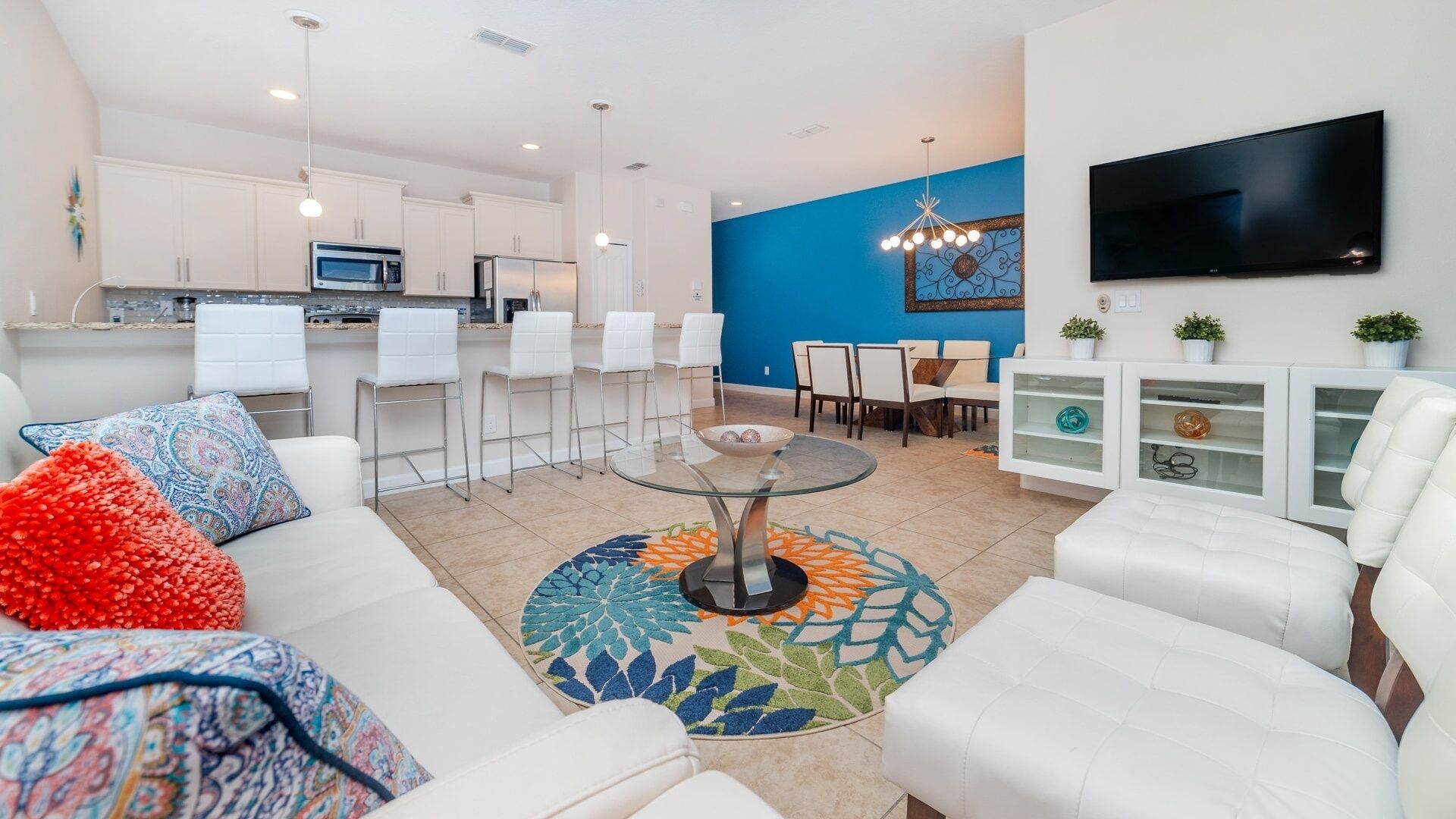 A modern living room with a white sofa, a glass coffee table, and a colorful rug.