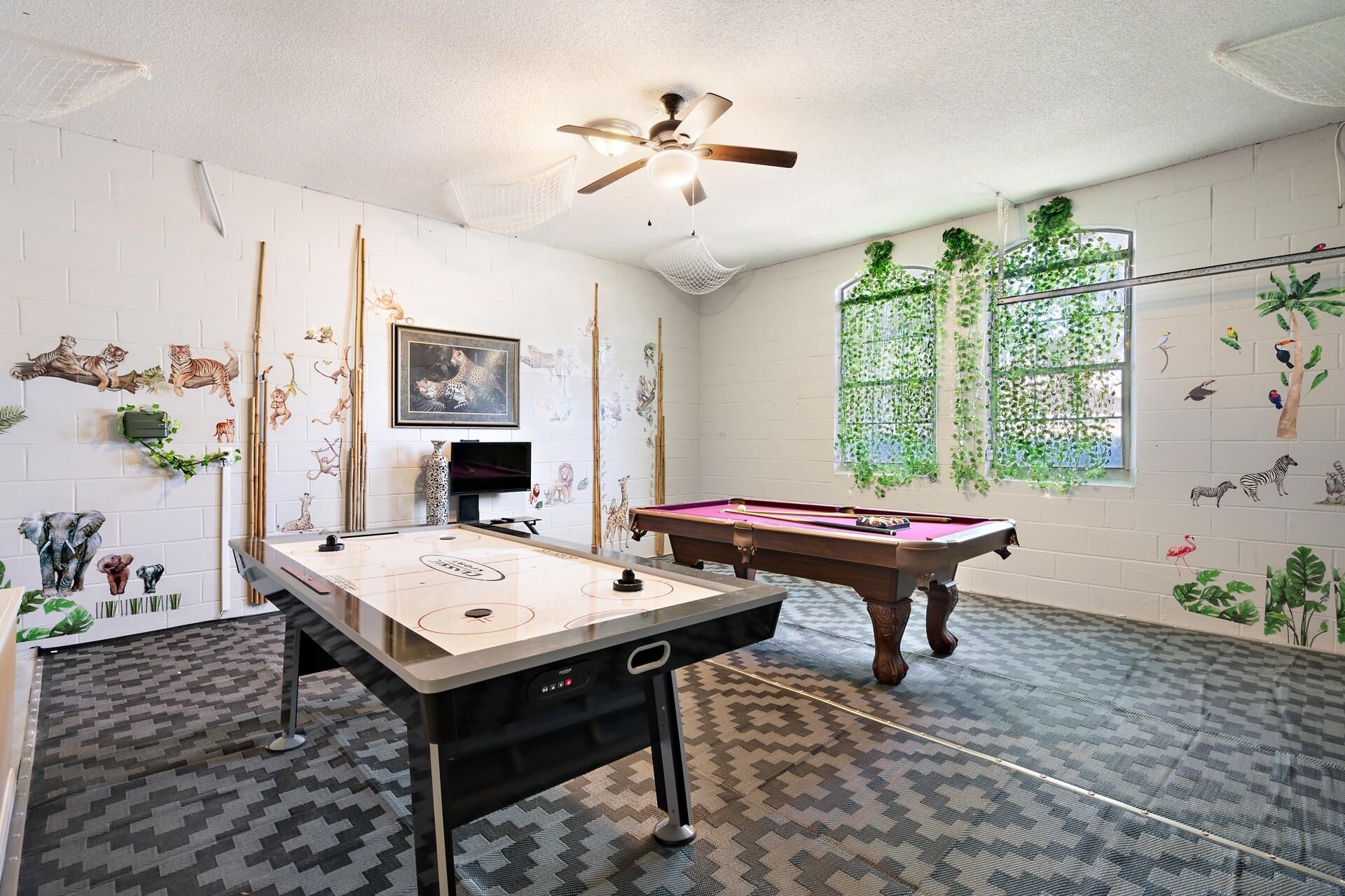 Une pièce équipée d’une table de billard, d’un baby-foot et d’un ventilateur de plafond.