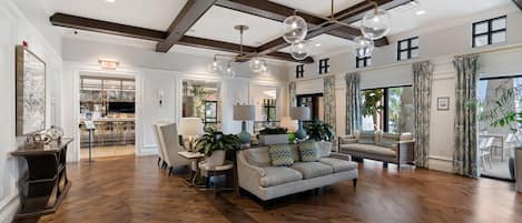 A spacious living room with a high ceiling, wooden flooring, and a large sofa set.