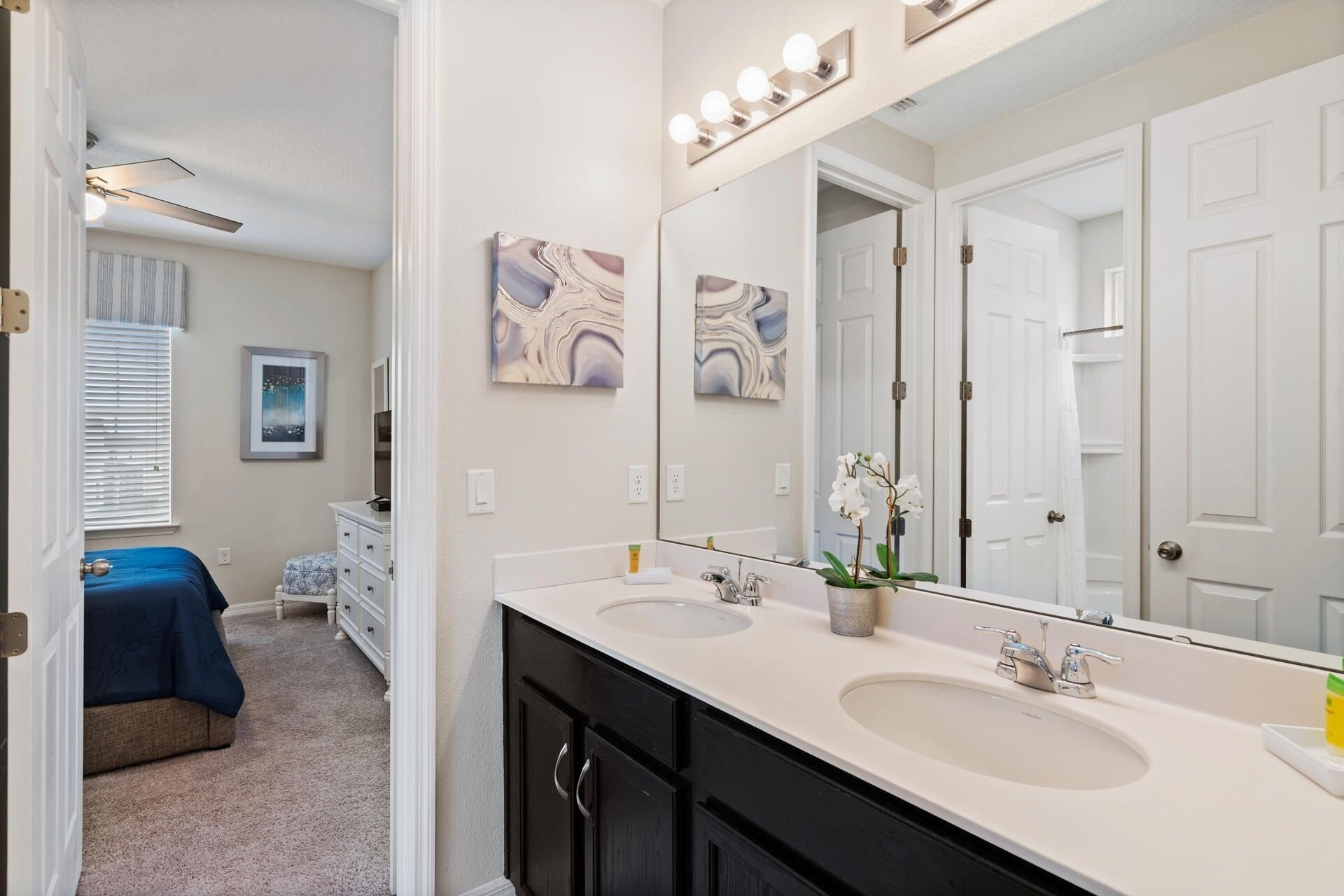 A bathroom with two sinks, a large mirror, and a vanity with drawers.