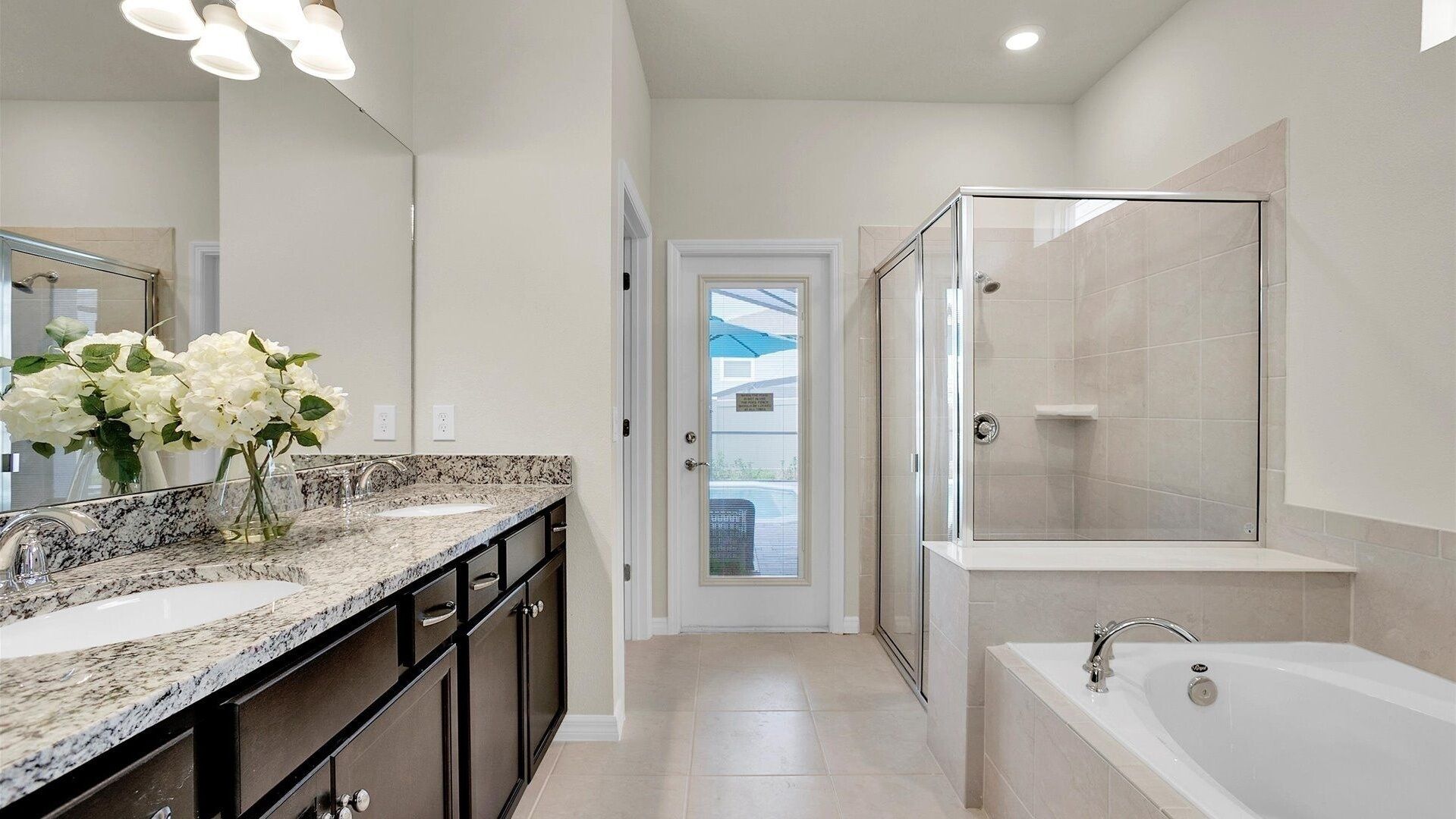 A modern bathroom with a double sink vanity, a glass shower enclosure, and a standalone bathtub.