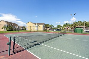 An outdoor tennis court with a net, surrounded by a fence, and adjacent to residential buildings. - Sweetwater Club 3 Bedroom Condo 7 miles to Disney 3 Condo (Kissimmee)