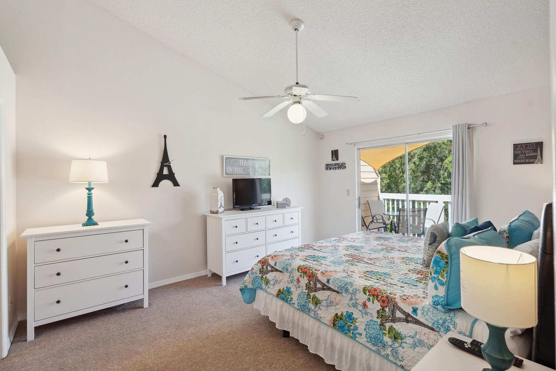 A bedroom with a bed, dresser, lamp, and a ceiling fan.