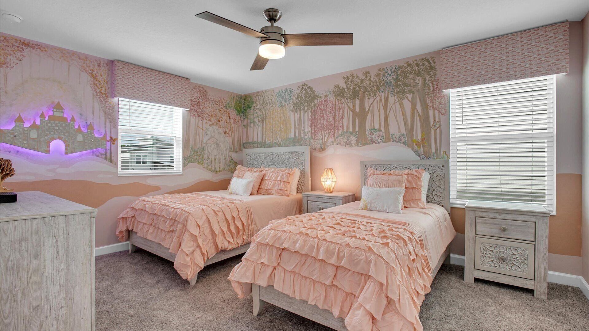 Une chambre avec deux lits, un ventilateur de plafond et une fresque murale.