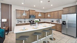 A modern kitchen with a central island, stainless steel appliances, and pendant lighting. - Windsor Island Resort 10 Bedroom Themed Private Home with Pool+Spa & Resort Amenity Access 10 Home (Davenport)