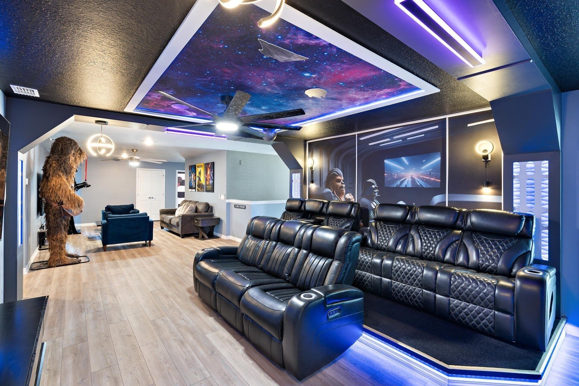 A home theater room with a starry ceiling, leather recliners, and a dog standing by the door.