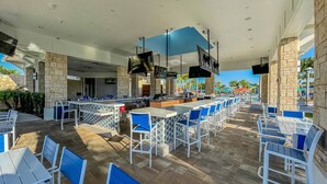 An outdoor bar area with multiple seating arrangements, including bar stools and tables, and a poolside view. - New 10 Br/19 Beds Pool+spa Disney Fireworks View 10 Bedroom Home (Davenport)