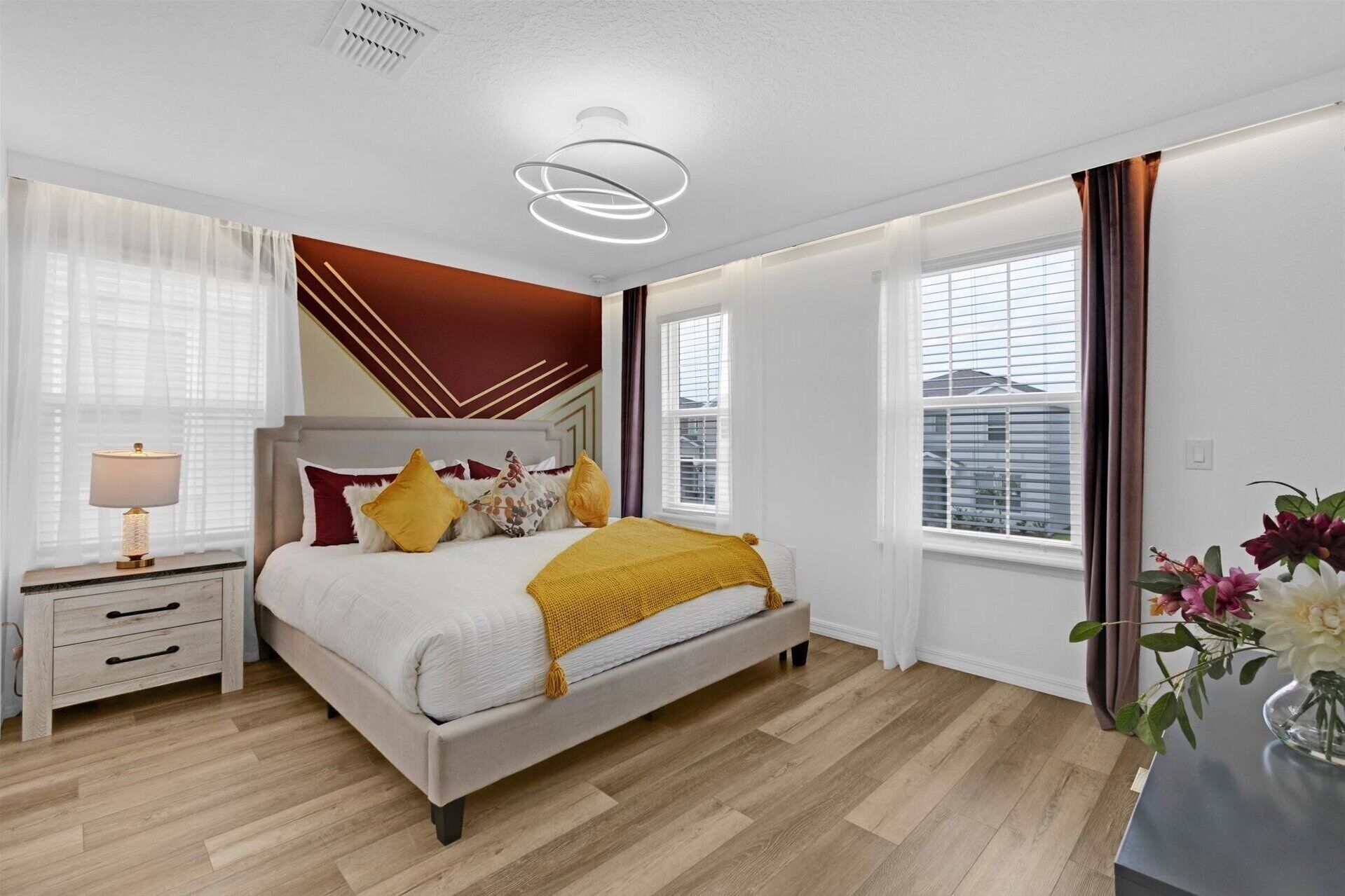 Ein modernes Schlafzimmer mit Bett, Nachttisch und einem Fenster mit Vorhängen.