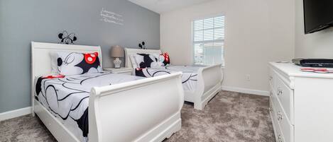 A bedroom with two beds, a ceiling fan, a window with blinds, and a TV on a stand.