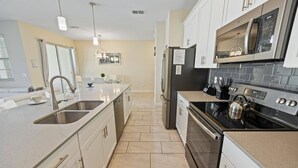 A modern kitchen with stainless steel appliances, a double sink, and a gas stove. - Storey Lake Resort 4 Bedroom Private Pool Townhome 4 Townhouse (Kissimmee)
