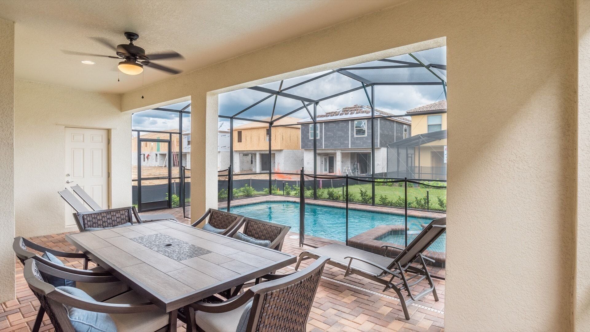 Une terrasse couverte avec une piscine, du mobilier d’extérieur et une vue sur les maisons voisines.