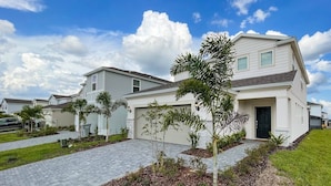 A modern residential building with a two-story design, a covered driveway, and well-maintained landscaping. - Windsor Island Resort 5 Bedroom East Facing Pool 5 Home (Davenport)