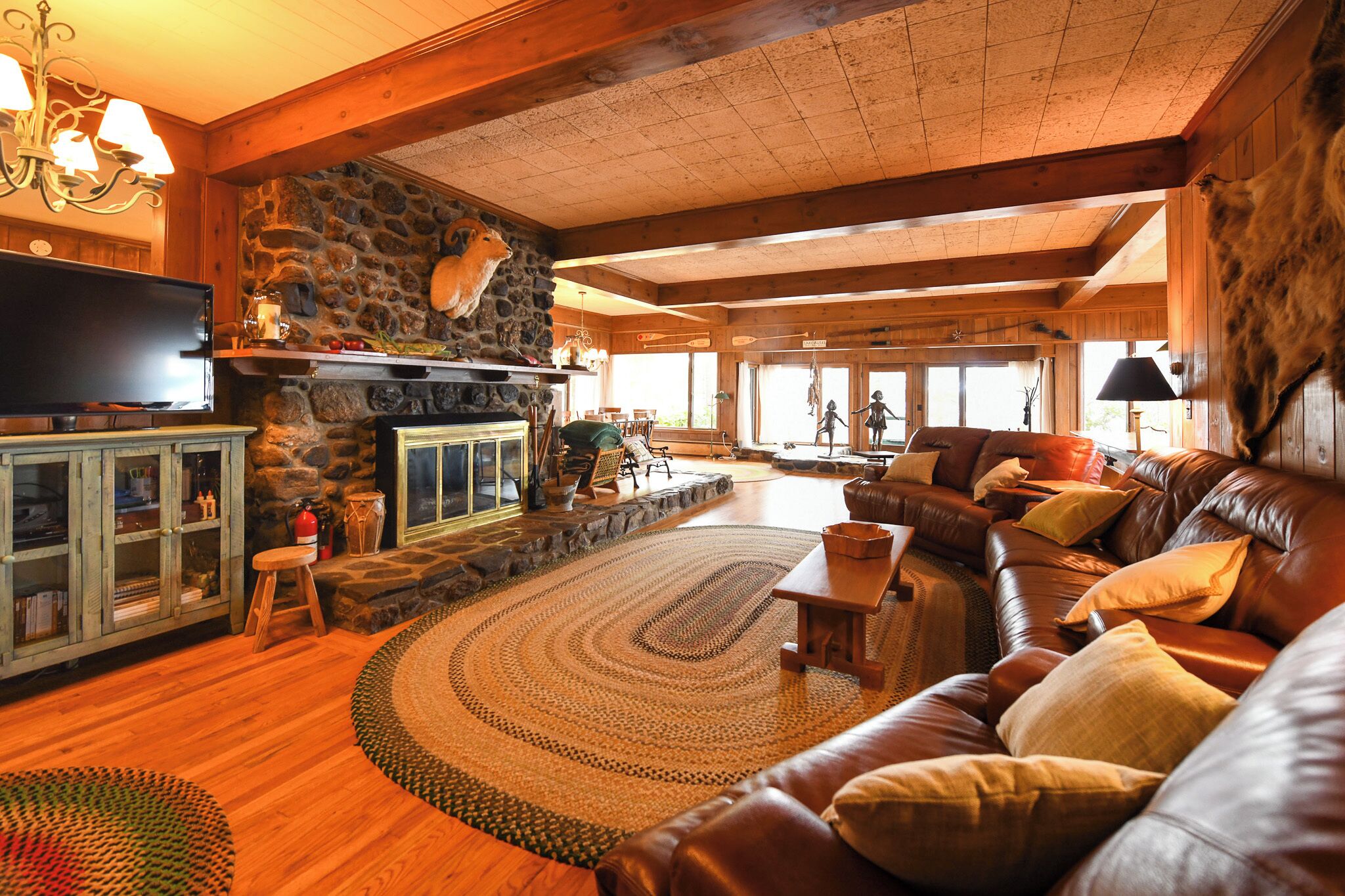 A cozy living room with a stone fireplace, leather sofa, and a television.