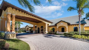 A hotel entrance with a covered walkway, palm trees, and a paved driveway. - Paradise Palms Resort 4 Bedroom Private Pool Townhome 4 Townhouse (Kissimmee)