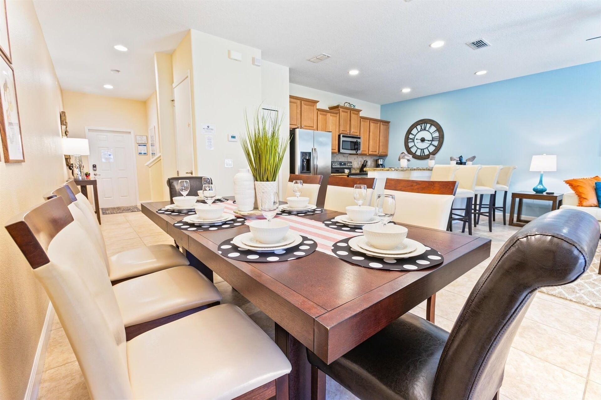 A dining area with a long table set for four, surrounded by chairs.