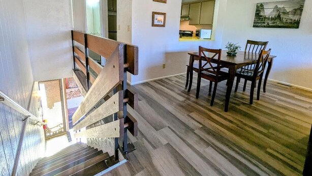 A staircase leading to a dining area with wooden flooring and a table with chairs. - Charming Forest Retreat – Steps from Snow Summit Slopes (Big Bear Lake)