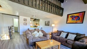 A spacious living room with two sofas, a coffee table, and a staircase. - Charming Forest Retreat – Steps from Snow Summit Slopes (Big Bear Lake)