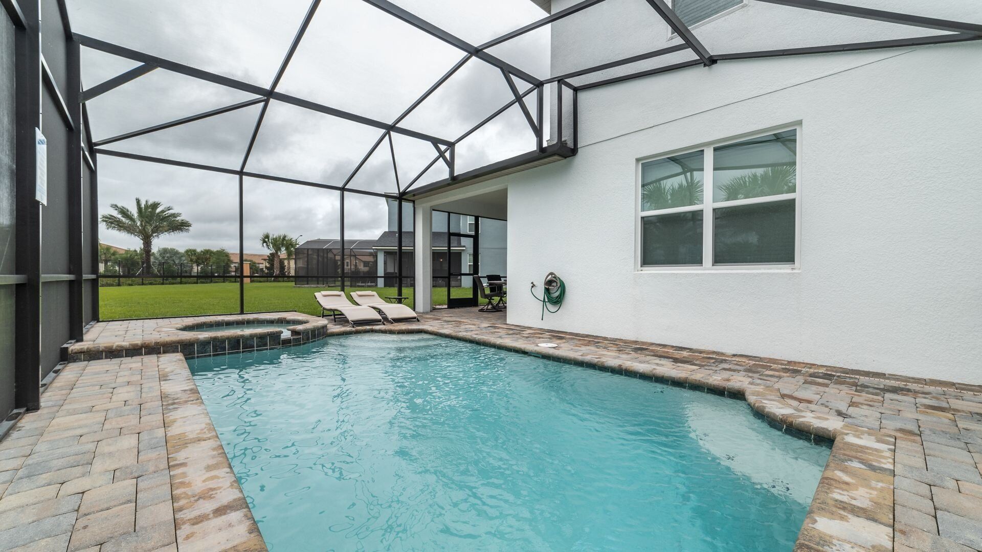 A swimming pool with a covered area, lounge chairs, and a view of the surrounding landscape.