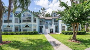 A two-story house with a covered front porch, a central entrance, and a well-maintained lawn. - Royal Palm Bay 3-Bedroom Vacation Condo with Amenity Access 3 Condo (Kissimmee)