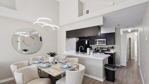 A modern kitchen with a central island, built-in appliances, and a dining area with a round mirror and pendant lighting. - Royal Palm Bay 3-Bedroom Vacation Condo with Amenity Access 3 Condo (Kissimmee)