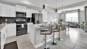 A modern kitchen with white cabinets, stainless steel appliances, and a central island with bar stools. - Storey Lake Resort 2 Bedroom Condo with Private Balcony 2 Condo (Kissimmee)