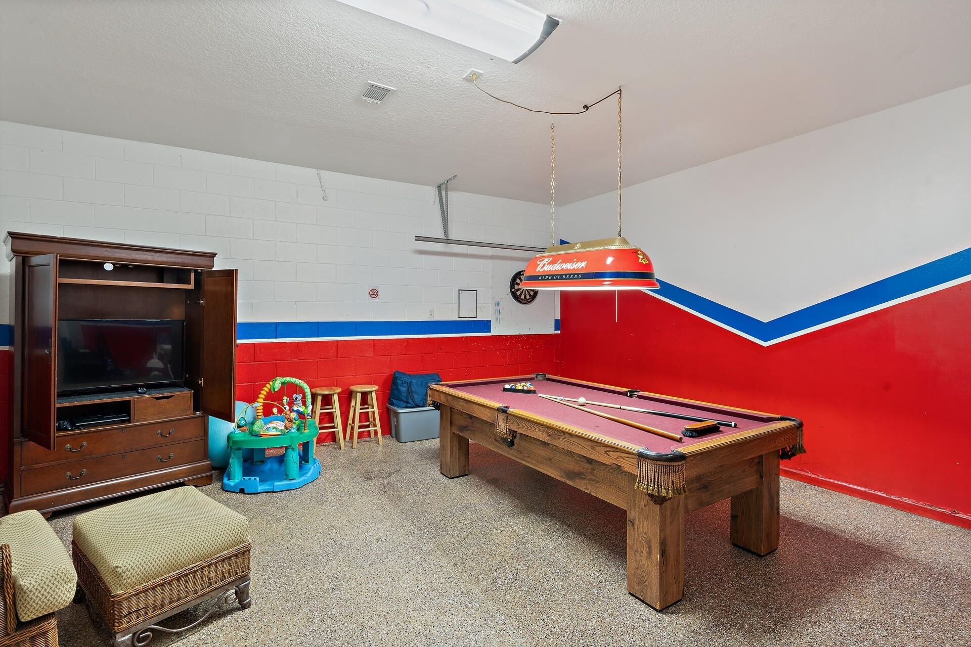 Una habitación con mesa de billar, televisor y decoración en la pared con diseño azul y rojo.