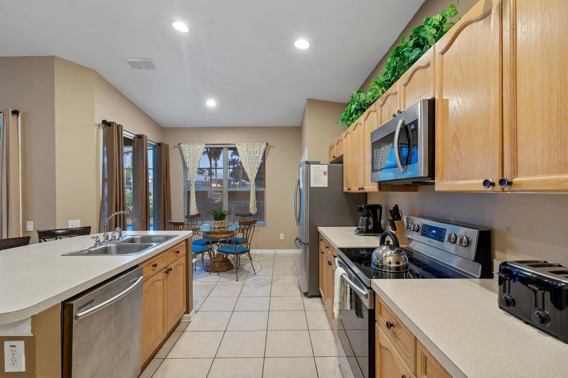 A modern kitchen with wooden cabinets, stainless steel appliances, and a dining area with a view.