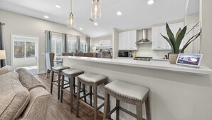 A modern kitchen with a central island, bar stools, and pendant lighting. - Private Pool~Sleeps 10~Golf Cart 6 Passenger Included~Walk to beach (Destin)