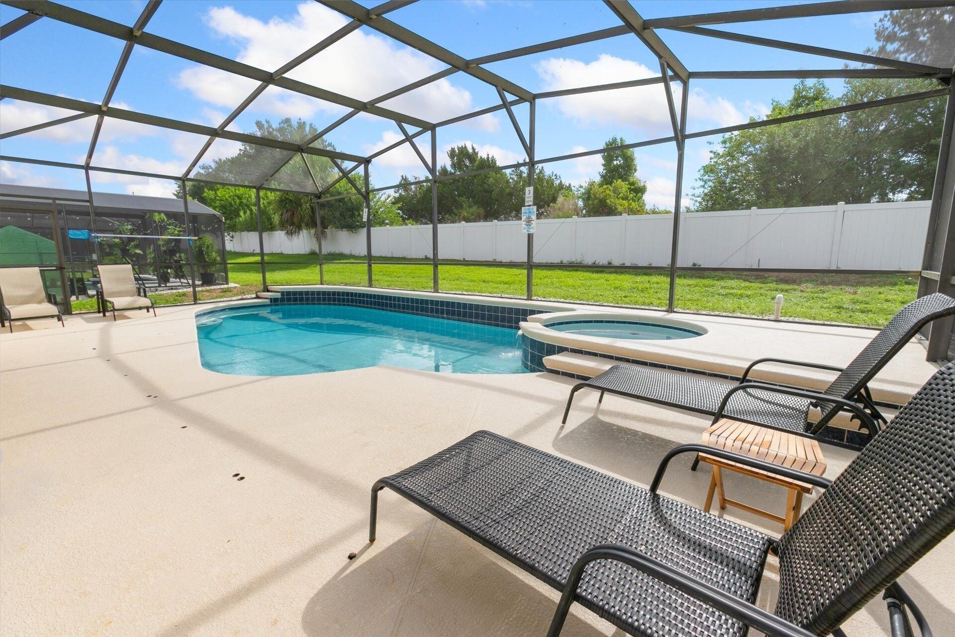A covered outdoor swimming pool with lounge chairs and a hot tub.