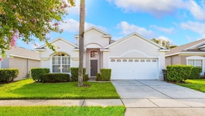 A residential house with a white exterior, a garage, and a well-maintained lawn. - Windsor Palms Resort 4 Bedroom Private Pool Home 4 Home (Kissimmee)