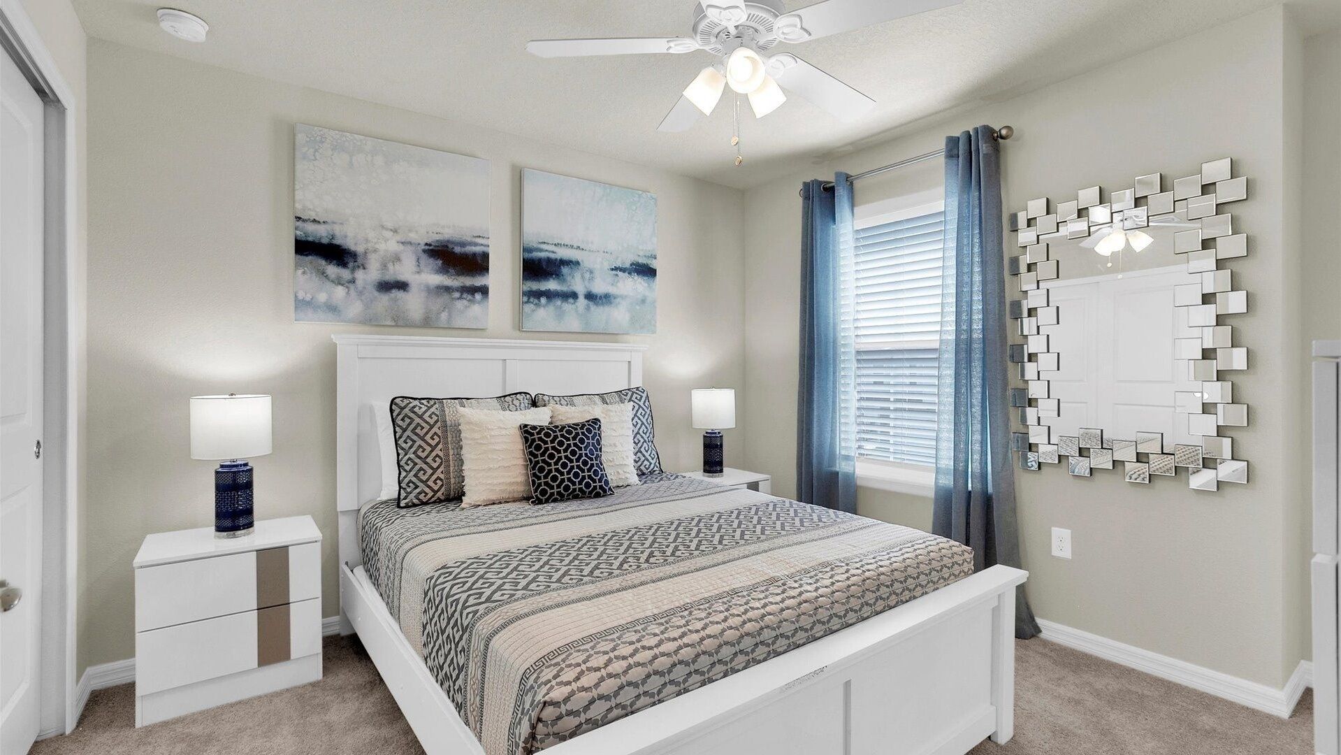 Camera da letto con un letto, comodini, ventilatore a soffitto, opere d'arte e uno specchio decorativo.