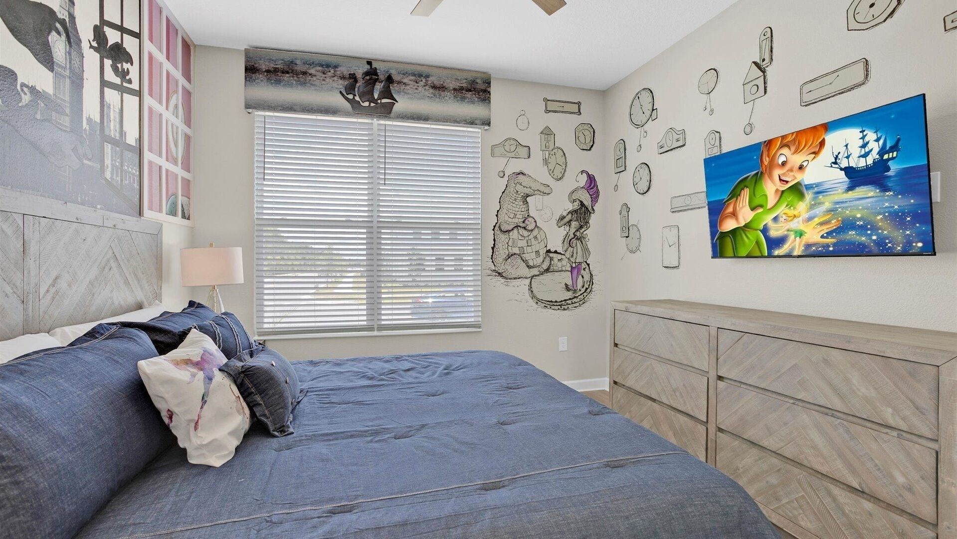 Un dormitorio con una cama, una ventana con persianas, una pared con relojes y un televisor mostrando un personaje de dibujos animados.