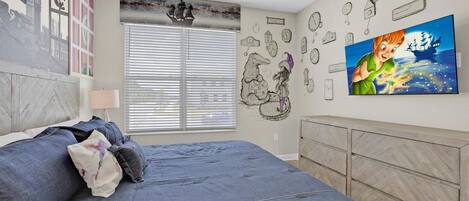 Un dormitorio con una cama, una ventana con persianas, una pared con relojes y un televisor mostrando un personaje de dibujos animados.