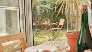 Une terrasse avec une table dressée pour deux personnes, une bouteille de vin et une plante en pot.