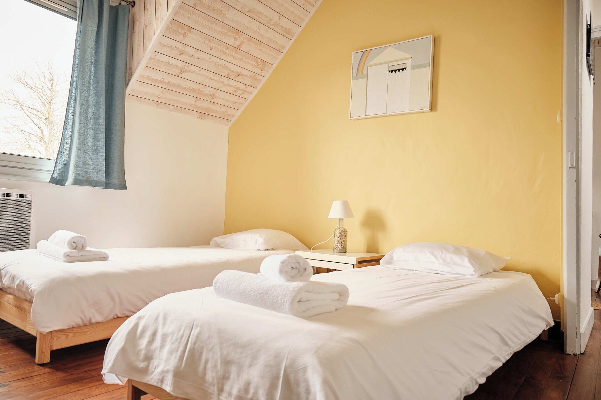 Ett hotellrum med två sängar, en lampa och ett fönster med gardiner.