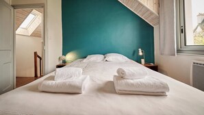 Une chambre avec un grand lit, un mur d’accent de couleur turquoise et un puits de lumière.