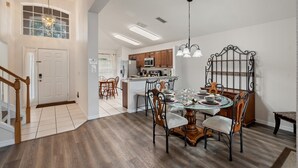 A spacious dining area with a wooden table and chairs, a kitchen in the background, and a staircase leading to another level. - Highlands Reserve 4 Bedroom Vacation Home with Private Pool 4 Hotel Room (Davenport)