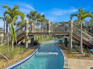 A pool area with a water slide, palm trees, and a wooden bridge. - Storey Lake Resort 5 Bedroom Private Pool Home 5 Home (Kissimmee)