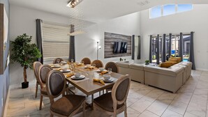 A modern dining area with a wooden table, chairs, and a chandelier. - Storey Lake Resort 5 Bedroom Private Pool Home 5 Home (Kissimmee)