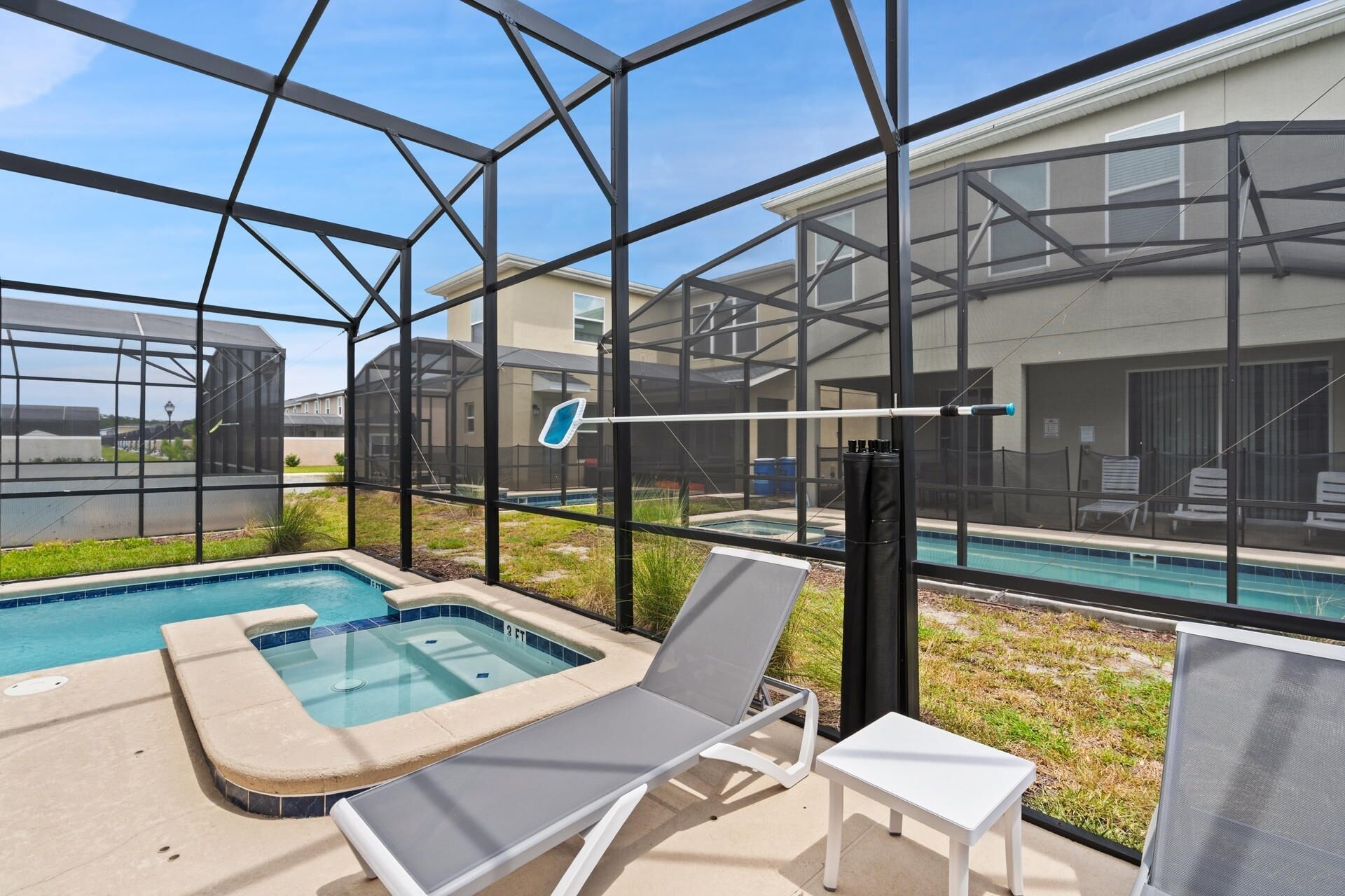 Un área de piscina con jacuzzi, sillas de descanso y una mesa.