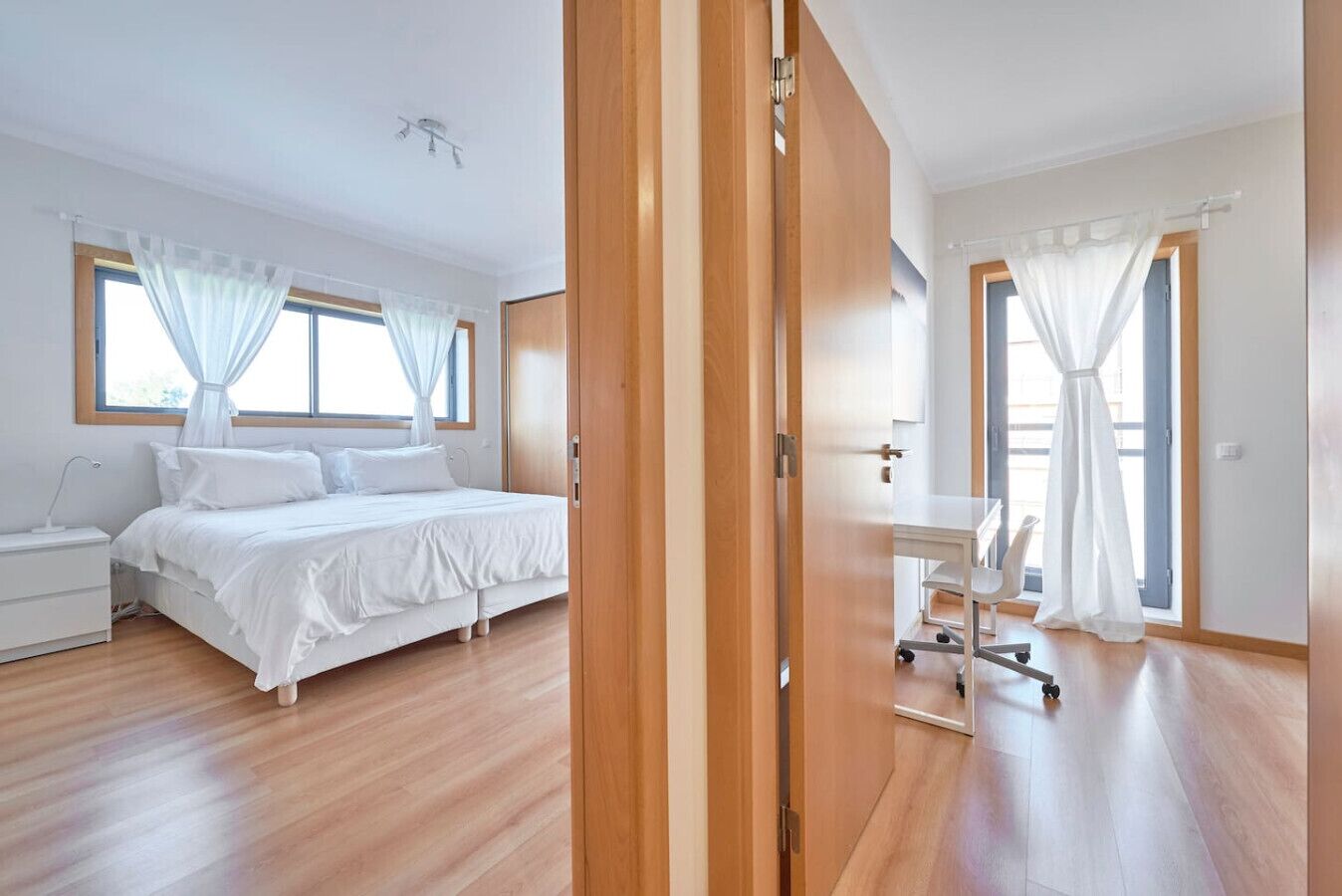Une chambre à coucher moderne avec un lit, une table de chevet et un bureau avec une chaise.