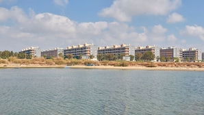 Een hotel aan het water met meerdere gebouwen, een zandstrand en rustig water.