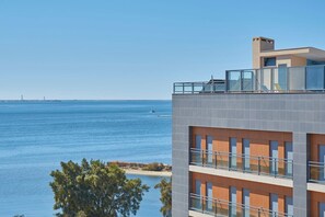 Ein modernes Gebäude mit Balkon und Blick auf ein Gewässer, mit freiem Blick auf das Meer und entfernte Landstrukturen.